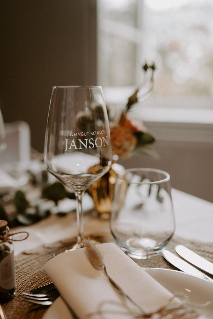 Hochzeitstisch im Weingut Schloss Janson mit stilvoll gedecktem Platz und personalisiertem Glas